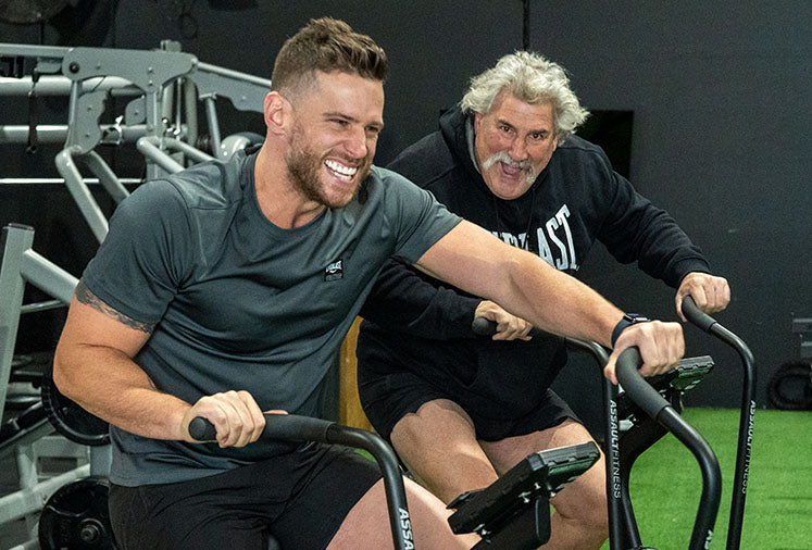 Dipper and Trainer smiling on Assault Bike Pro | Gym and Fitness Membership Program